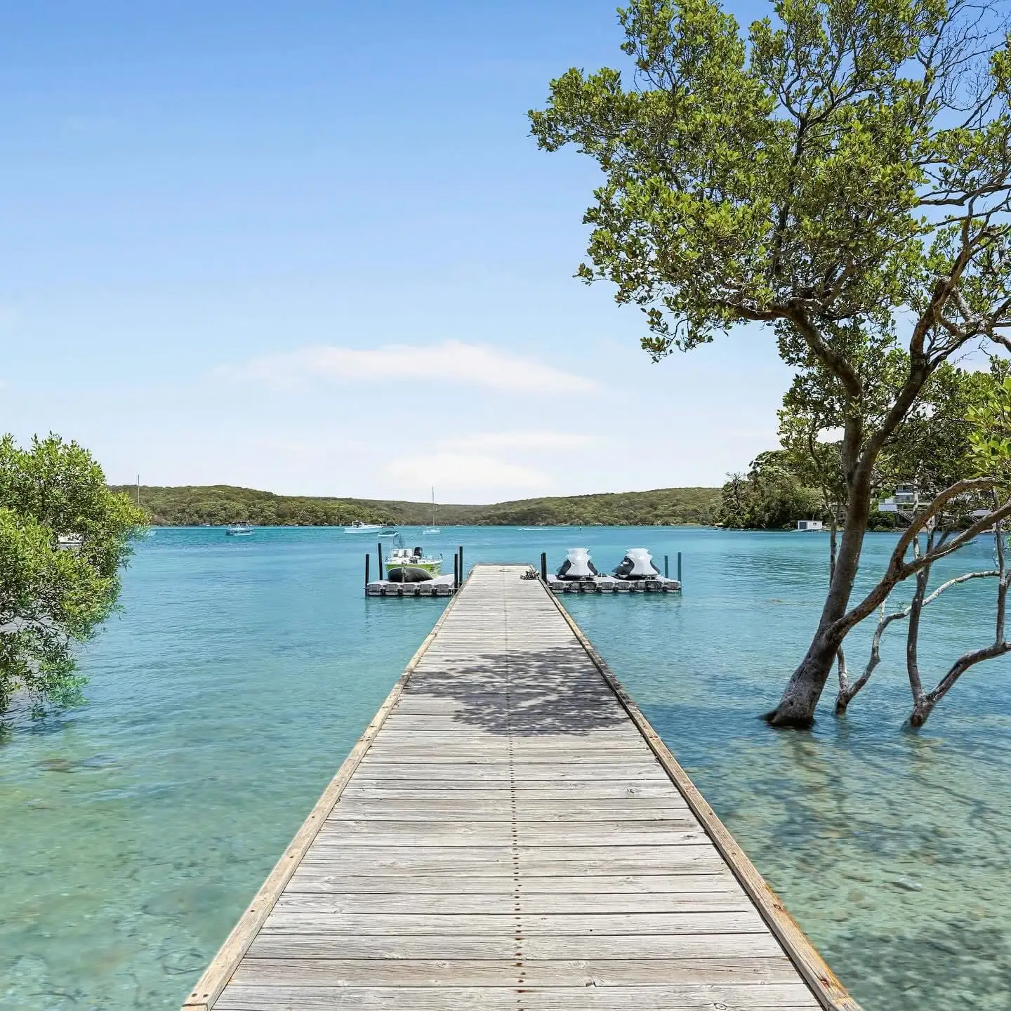 Timber jetty with white handrails built by Kingtide Marine reaching over the clear water of the Port Hacking River